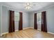 Minimalist bedroom featuring wood-look floors, neutral paint, and two windows dressed with brown curtains at 424 N Green Cir, Mcdonough, GA 30252