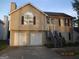 Two-story tan home with a chimney, dark shutters, a basement garage, and a small set of stairs at 2338 Rambling Way, Lithonia, GA 30058