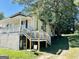 Charming home exterior featuring a covered porch, access stairs, and lush greenery at 7 Ivy St, Porterdale, GA 30014