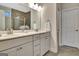 Bathroom features dual sinks, vanity with white cabinets, decorative mirror, and tiled shower at 609 Francis Ave, Peachtree City, GA 30269