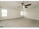 Large bedroom with neutral carpet, ceiling fan, and natural light from two windows at 3675 Arminto Dr, Ellenwood, GA 30294