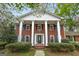 Traditional red brick home boasts a symmetrical facade with white columns, black shutters, and blooming dogwoods at 173 Darwish Dr, Mcdonough, GA 30252