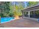 Exterior view of the back of the home with a pool and wooden deck surrounded by lush greenery at 203 Silverwood Way, Peachtree City, GA 30269