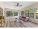 Bright sun room with large windows offering views of the backyard, wood-look floors, and a comfortable couch at 203 Silverwood Way, Peachtree City, GA 30269