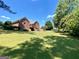 Well-maintained backyard with mature trees, green lawn, and partially-visible deck and hot tub at 103 Wisteria Way, Stockbridge, GA 30281