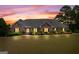 Beautifully landscaped front yard with a well-lit single-story brick home at sunset at 103 Wisteria Way, Stockbridge, GA 30281