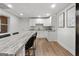 This kitchen features white cabinets, stainless steel appliances, a marble countertop eating area, and wood floors at 103 Wisteria Way, Stockbridge, GA 30281