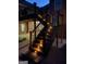 Exterior staircase with warm lighting leading to a deck, set against a backdrop of brick and greenery at 103 Wisteria Way, Stockbridge, GA 30281
