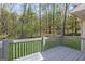A gray wooden deck offers a relaxing view of a backyard with mature trees and green grass at 185 Cold Harbor Ct, Sharpsburg, GA 30277