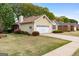 Beautiful exterior view of the house showing a well-manicured lawn, flower bushes, and a two-car garage at 210 Brittany Chase, Fayetteville, GA 30214