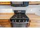 A close-up of a black gas stove top featuring four burners and stainless-steel knobs and accents at 210 Brittany Chase, Fayetteville, GA 30214