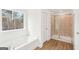 Bright bathroom featuring a soaking tub beneath a window and a separate tiled shower at 7260 Eton Ln, Locust Grove, GA 30248