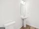Simple powder room featuring wood-look floors, pedestal sink, and toilet at 7260 Eton Ln, Locust Grove, GA 30248