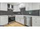 Kitchen with stainless steel appliances, white cabinets, updated fixtures, and Herringbone backsplash at 3387 Oak Dr, Lawrenceville, GA 30044