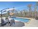 A backyard pool surrounded by lounge chairs, umbrellas, and wooded privacy at 270 Blue Point Pkwy, Fayetteville, GA 30215