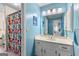 A full bathroom with a single sink vanity, large mirror, and shower with colorful curtain at 105 Hartford Pl, Fayetteville, GA 30214