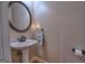 Elegant half bathroom featuring a pedestal sink, decorative mirror, and stylish fixtures at 1730 Carlington Ct, Grayson, GA 30017