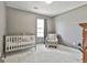 Cozy bedroom featuring neutral walls and carpeting, with a crib and patterned accent chair at 1109 Allen Rd, Grantville, GA 30220
