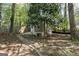 View of detached structure in shaded backyard with mature trees, stone path and wood fence at 385 Lakeshore Dr, Stockbridge, GA 30281