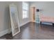 Bright bedroom with wood floors, plush bench, and door leading to a bathroom at 1461 Thomas St, Conyers, GA 30094
