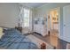 Well-lit bedroom with dark hardwood floors, doorway to bathroom, and windows with floral curtains at 1461 Thomas St, Conyers, GA 30094
