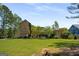 Spacious backyard showcasing the home's exterior, a well-maintained lawn, and mature trees for privacy at 240 Trotters Rdg, Fayetteville, GA 30215