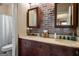 Rustic bathroom with brick accent wall, dual sinks, and wood cabinets at 240 Trotters Rdg, Fayetteville, GA 30215