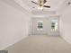 Spacious primary bedroom with neutral carpet, ceiling fan, tray ceiling, and natural light from two windows at 335 Silver Moon Dr, Loganville, GA 30052