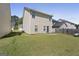 View of a backyard featuring a lawn and the home's rear exterior with tan siding and windows at 7756 Newbury Dr, Jonesboro, GA 30236
