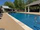 Sparkling inground pool surrounded by a concrete patio, complemented by lush landscaping and clear blue skies at 363 Palmetto Rd, Tyrone, GA 30290