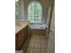 Bright bathroom featuring a soaking tub with large window, vanity, and tiled floors at 45 Anna Dr, Covington, GA 30014