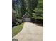 A detached brick garage with a concrete driveway is surrounded by lush greenery and mature trees at 45 Anna Dr, Covington, GA 30014