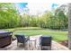Spacious backyard with lush green grass, wooded backdrop, hot tub, and stone patio with cozy seating at 145 Carrington Ln, Brooks, GA 30205