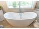 Elegant bathroom features a freestanding tub with a modern faucet, complemented by natural light from a window at 145 Carrington Ln, Brooks, GA 30205