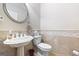 Elegant powder room featuring a pedestal sink, decorative mirror, and neutral tile at 2351 Rabbit Farm Cir, Loganville, GA 30052