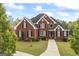 Impressive red brick home featuring manicured lawn, black shutters, and elegant architectural detailing at 2351 Rabbit Farm Cir, Loganville, GA 30052
