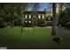Charming brick home at dusk, featuring manicured lawn, mature trees, and attached two car garage at 180 Paces Dr, Fayetteville, GA 30215
