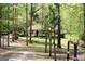View of a charming home down a long driveway, framed by a rustic fence and beautiful green trees at 206 Pine Cedar Cir, Brooks, GA 30205