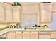 White cabinets and appliances in kitchen, with a double-basin sink and natural lighting at 144 Garden Walk, Stockbridge, GA 30281