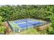 Aerial view of two well-maintained blue and green outdoor tennis courts surrounded by tall trees at 736 Mesa Rd, Mcdonough, GA 30253
