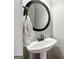 Stylish half bathroom features a modern pedestal sink and round mirror at 340 Hammersmith Dr, Suwanee, GA 30024