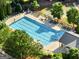 Community swimming pool surrounded by lounge chairs, landscaping, and lush, mature trees at 340 Hammersmith Dr, Suwanee, GA 30024