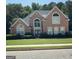 Charming brick home featuring a well-manicured lawn, manicured shrubbery, and a gray roof at 135 Danube Trl, Stockbridge, GA 30281