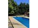 Refreshing pool area with sparkling blue water, surrounded by manicured landscaping and mature trees for privacy at 135 Danube Trl, Stockbridge, GA 30281