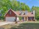 Charming two-story home with brick and vinyl siding, attached garage, manicured lawn, and mature trees at 2040 Elm Grove Ln, Hampton, GA 30228