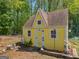A quaint yellow outbuilding is nestled among mature trees and greenery on the property at 2040 Elm Grove Ln, Hampton, GA 30228