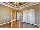 Main bedroom with hardwood floors, tray ceiling, and en suite bath at 10125 Brixton Pl, Suwanee, GA 30024