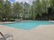 Community swimming pool surrounded by a black fence and trees with lounge chairs stacked nearby at 6281 Vinings Vintage Dr, Mableton, GA 30126