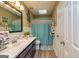 Well-lit bathroom with a white vanity, black framed mirror, toilet, and blue shower curtain at 310 Hamdon Kells, Peachtree City, GA 30269