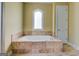 Bathroom featuring a large soaking tub, an arched window, and travertine tile surround at 345 Phillips Dr, Fayetteville, GA 30214